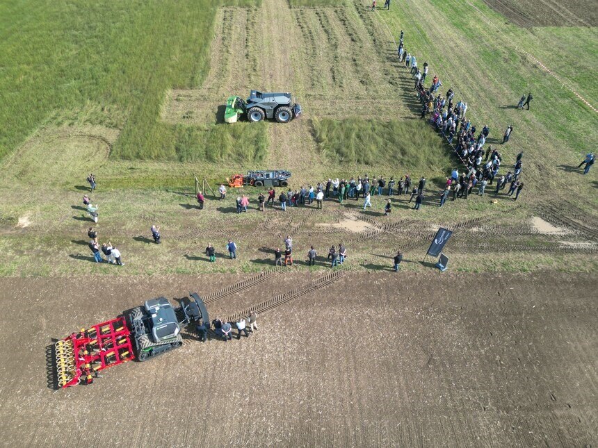 Das Bild wurde in Vogelperspektive aufgenommen und zeigt die Teilnehmer sowie Robotiklösungen auf dem Acker beim zweiten Köllitscher Feldrobotiktag.